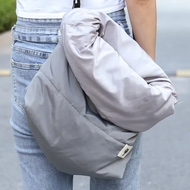 Person wearing a light gray crossbody bag with a blurred background