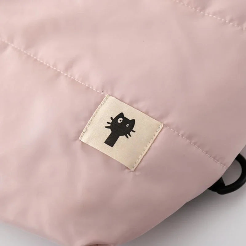 Close-up of a pink bag with a black cat logo on a beige label.