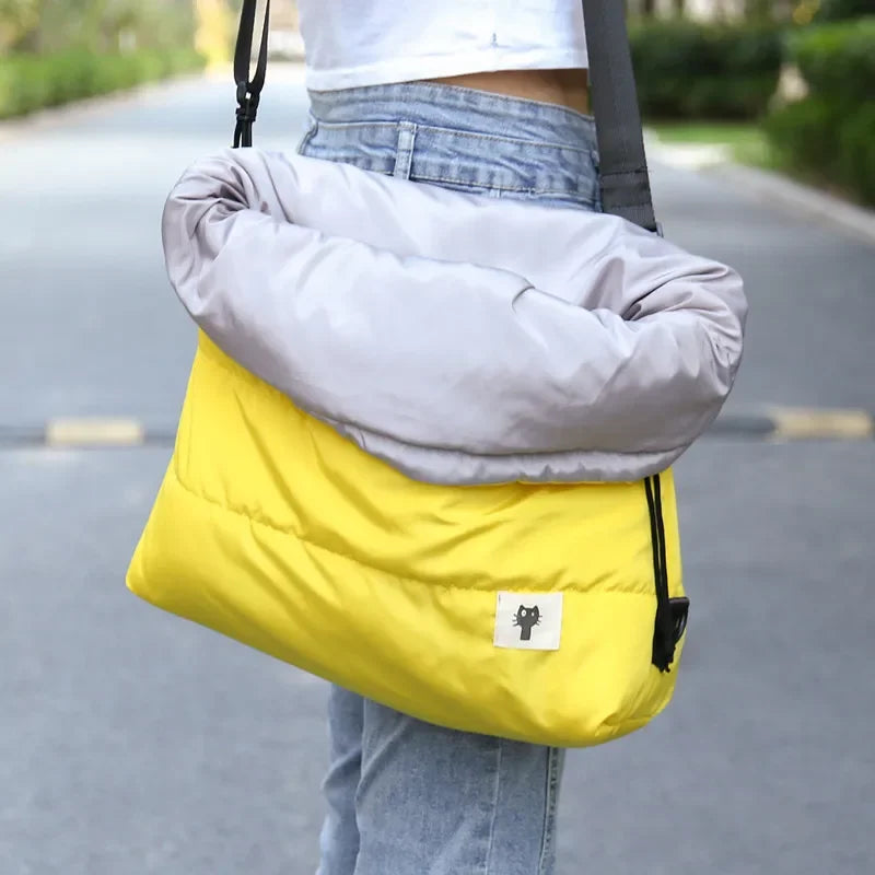 Person carrying a yellow and gray bag outdoors on a path