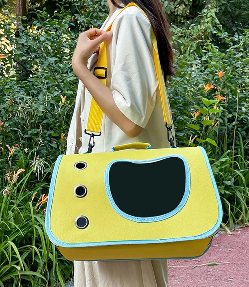 Person holding a yellow pet carrier with a green outdoor background