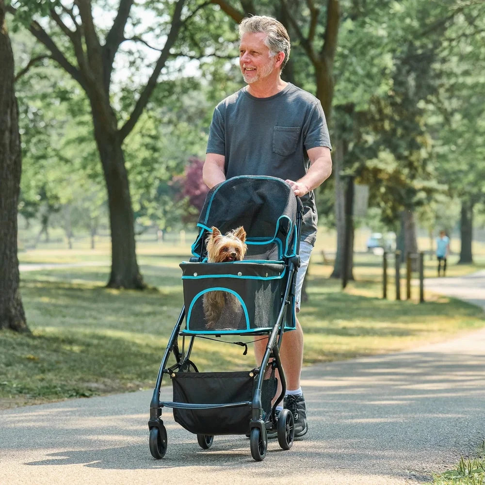 Man pushing a pet stroller with a dog in it through a park.