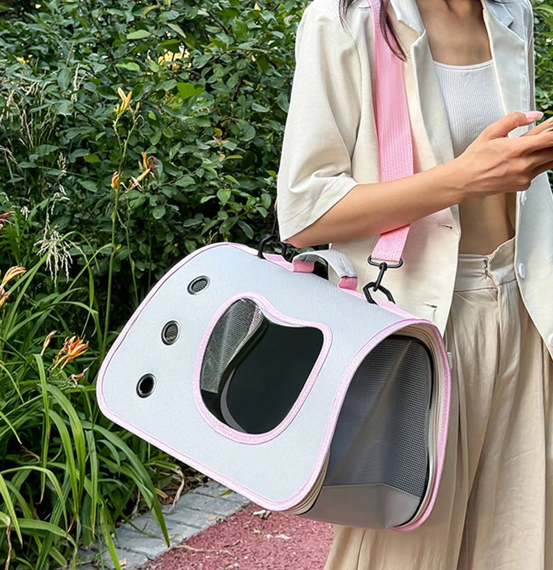 Person holding a pet carrier outdoors with greenery in the background
