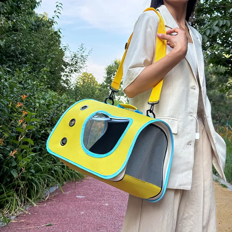 Person holding a yellow pet carrier outdoors with greenery in the background