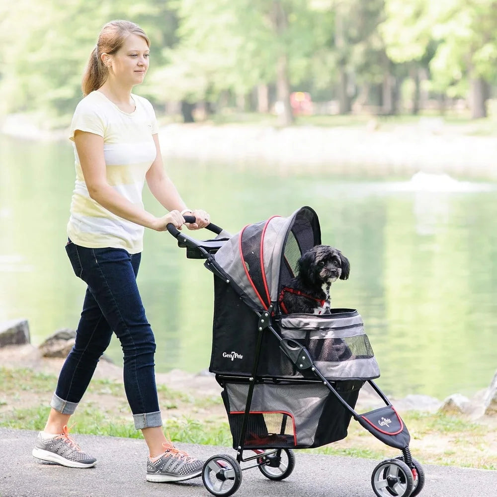 Woman pushing a pet stroller with a dog in it along a path by a lake.