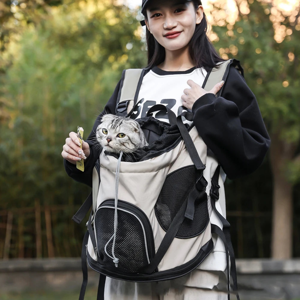 Person holding a cat in a backpack with a blurred green background