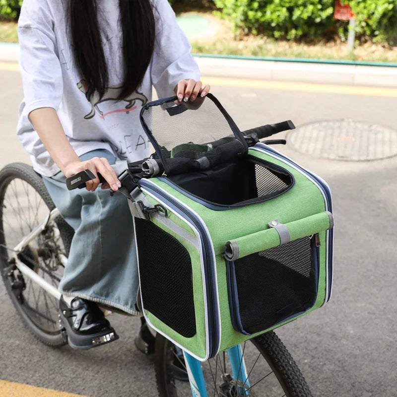 Person riding a bicycle with a green pet carrier attached to the back