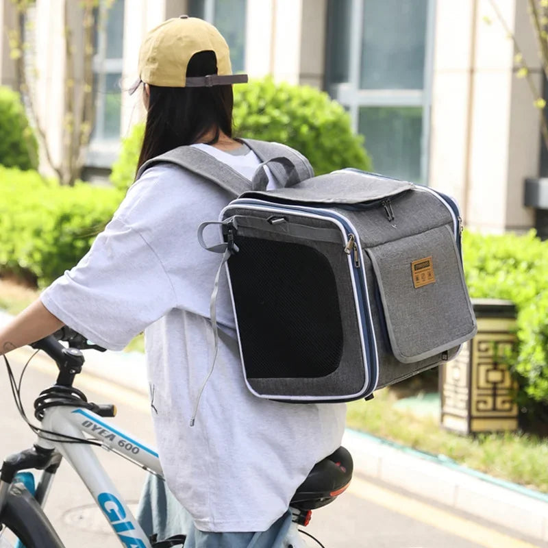 Person riding a bicycle with a gray pet carrier on their back