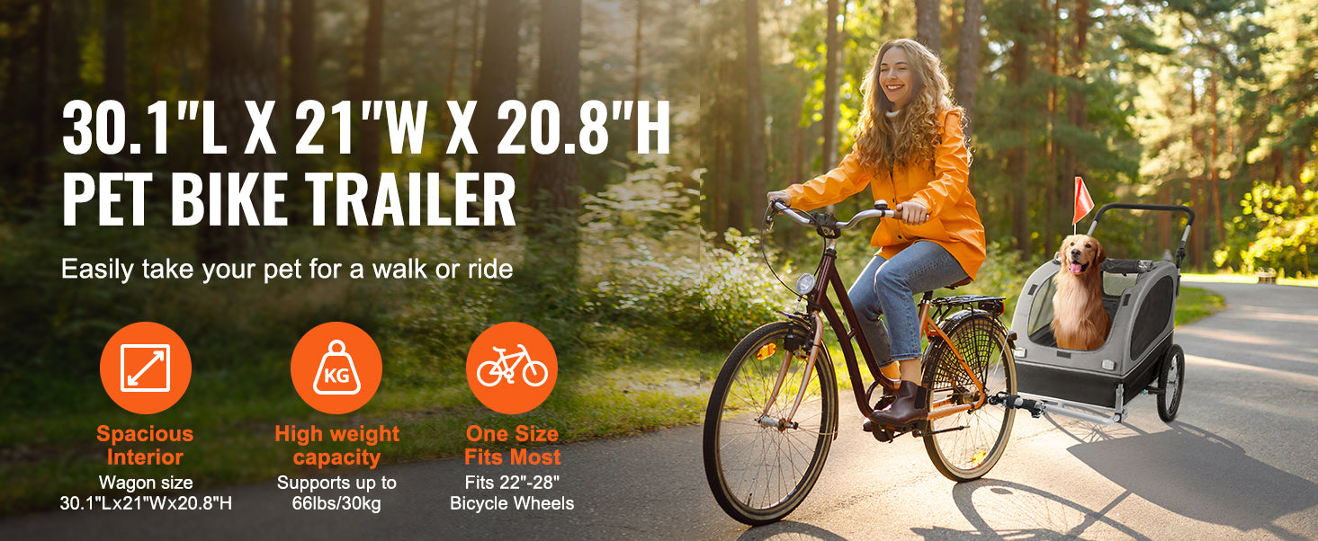 Woman riding a bike with a pet bike trailer attached, surrounded by trees and greenery.