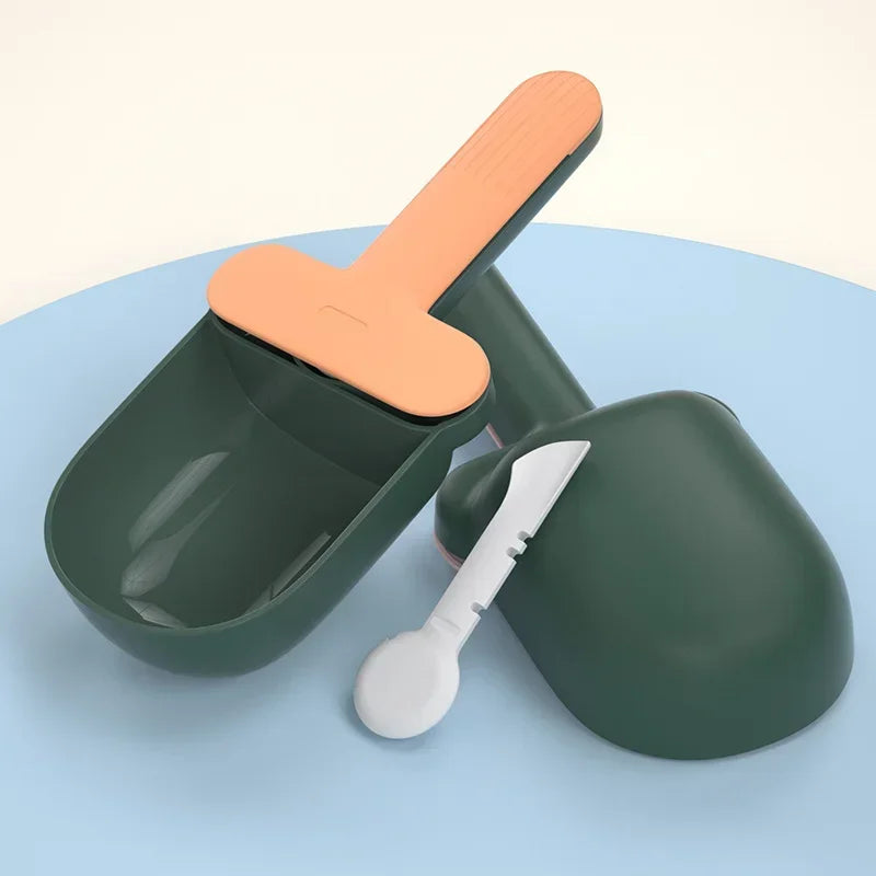 Green plastic ice cream scoop with orange handle on a light blue background