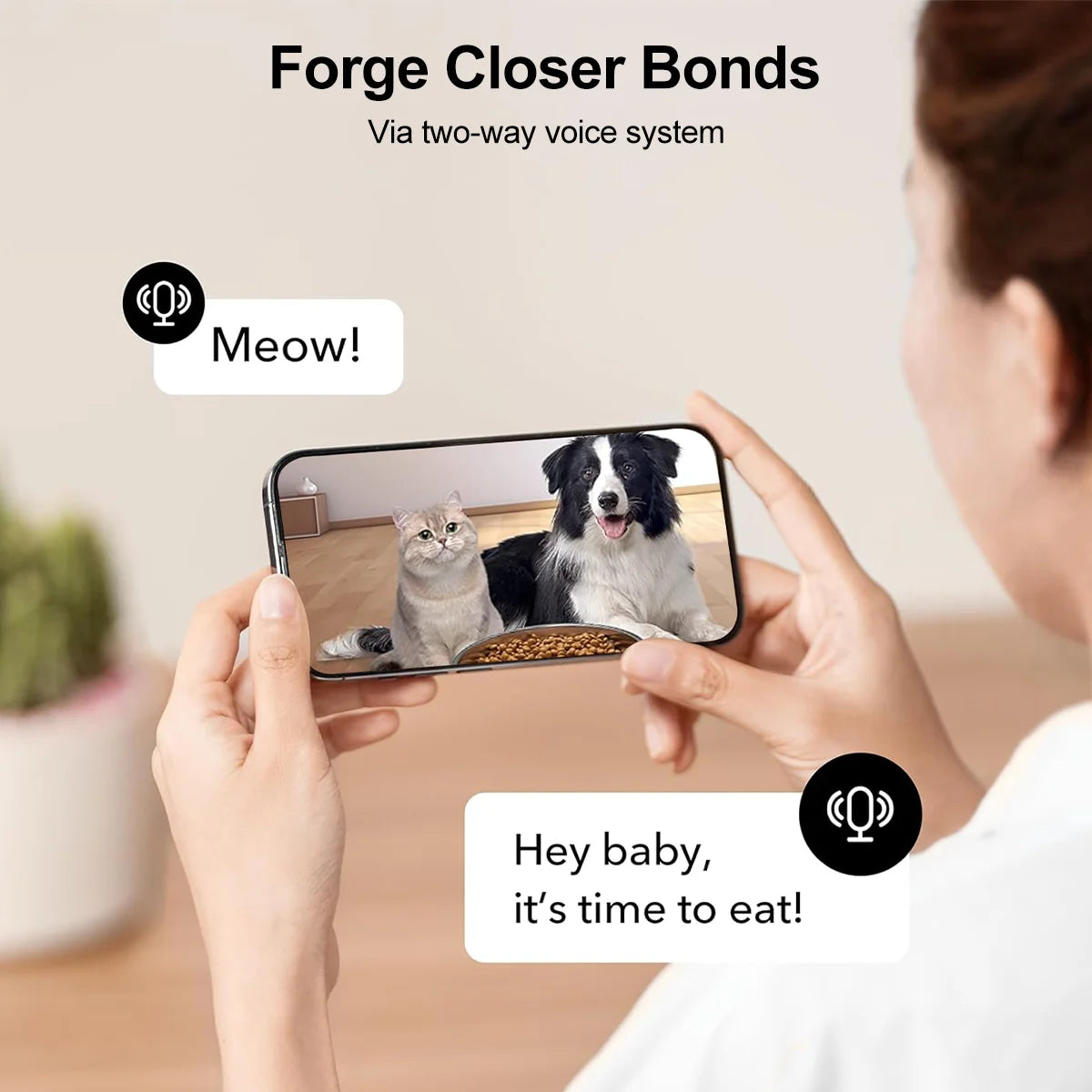 Person using a smartphone with a two-way voice system app showing a cat and dog, with text 'Meow!' and 'Hey baby, it's time to eat!'.